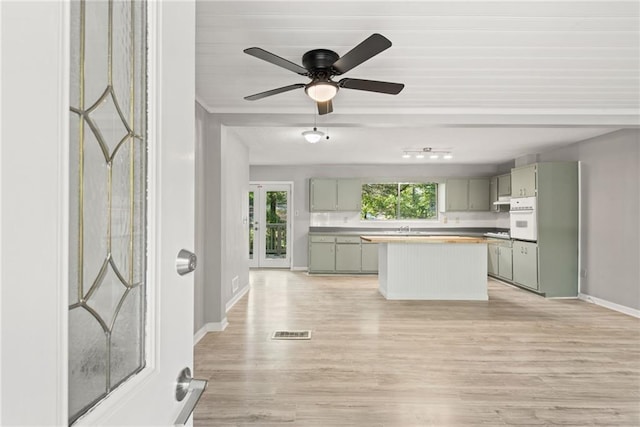 kitchen with gray cabinetry, ceiling fan, a center island, white oven, and light hardwood / wood-style flooring