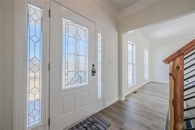 entrance foyer with ornamental molding, stairway, baseboards, and wood finished floors