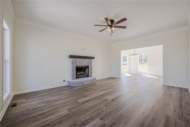 unfurnished living room with visible vents, ornamental molding, a brick fireplace, ceiling fan, and wood finished floors