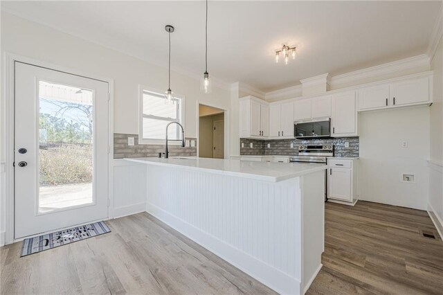 kitchen featuring light wood finished floors, light countertops, appliances with stainless steel finishes, white cabinetry, and a peninsula
