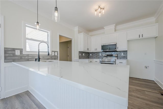 kitchen with white cabinets, stainless steel appliances, a sink, and wood finished floors