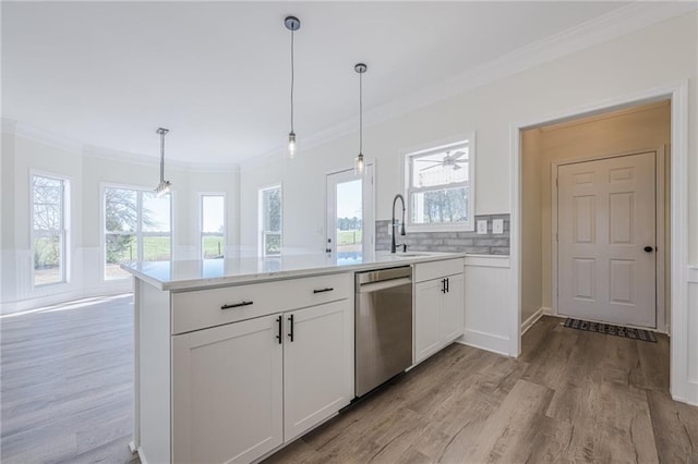 kitchen featuring light countertops, stainless steel dishwasher, ornamental molding, a sink, and a peninsula