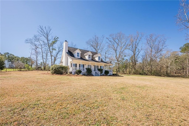 new england style home featuring a chimney, a front lawn, and a porch