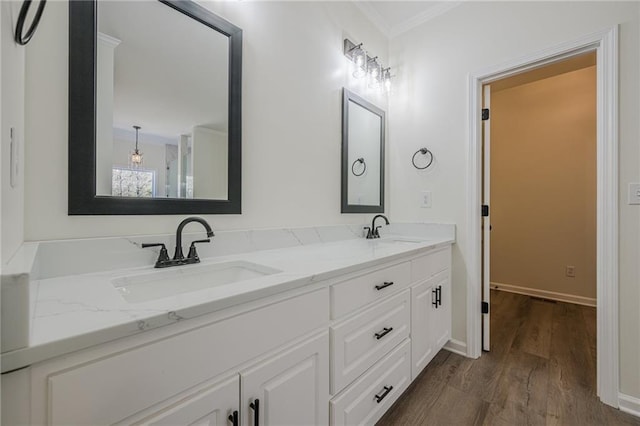 bathroom with ornamental molding, double vanity, wood finished floors, and a sink