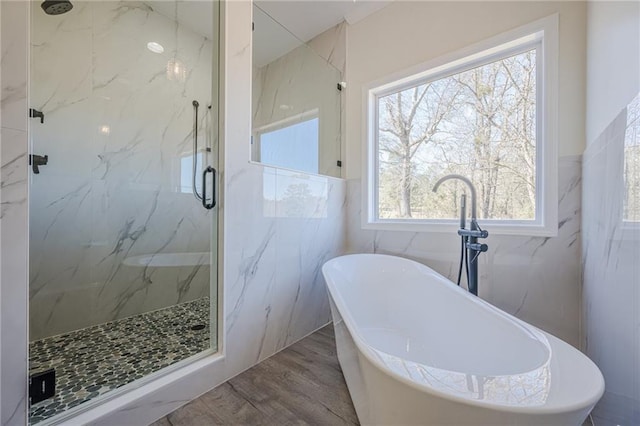 full bathroom featuring a soaking tub, tile walls, a marble finish shower, and wood finished floors