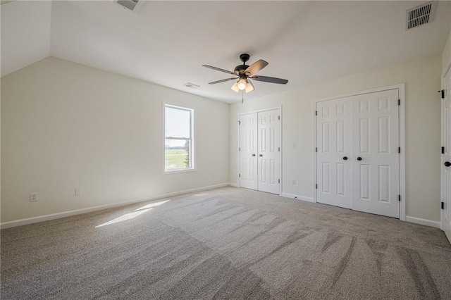 unfurnished bedroom with visible vents, multiple closets, and carpet flooring
