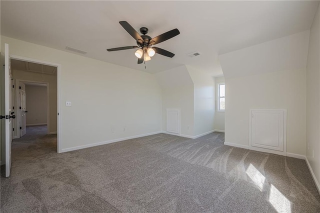 empty room with attic access, carpet flooring, vaulted ceiling, and baseboards