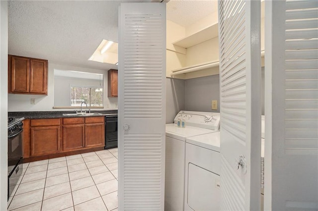 laundry area with sink, light tile patterned floors, washing machine and clothes dryer, and a textured ceiling