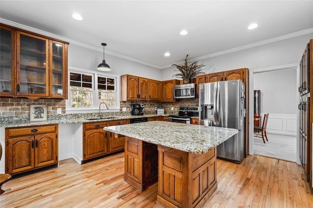 kitchen with brown cabinetry, a center island, stainless steel appliances, and a sink