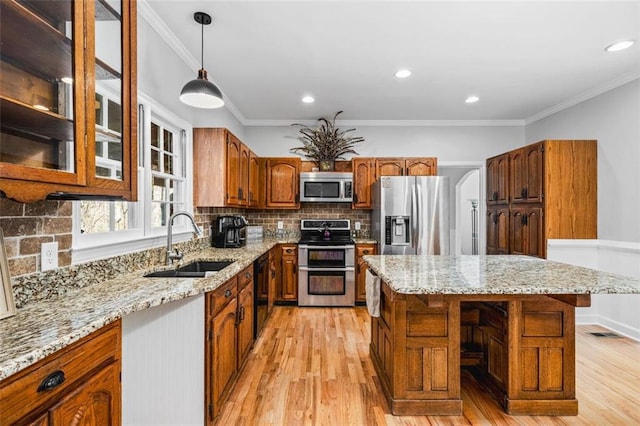 kitchen with a sink, stainless steel appliances, light wood-style floors, and brown cabinetry