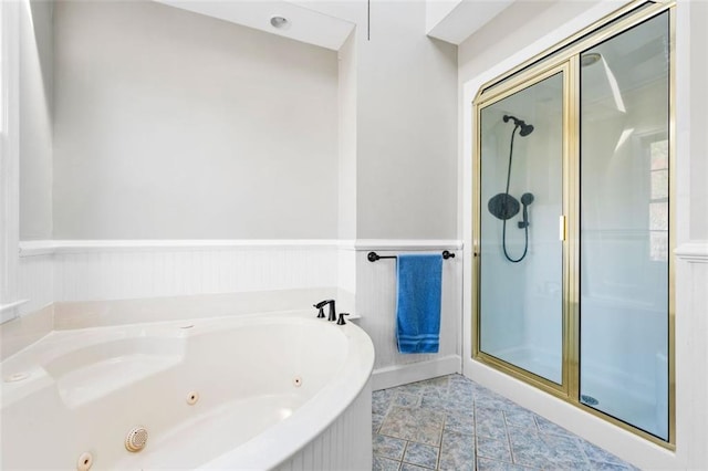 bathroom featuring a wainscoted wall, a jetted tub, and a stall shower