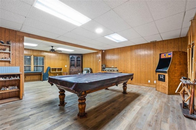 game room featuring billiards, wooden walls, light wood-style floors, and a drop ceiling