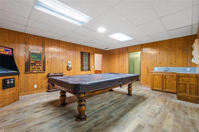 playroom with light wood-type flooring, a paneled ceiling, wood walls, and pool table