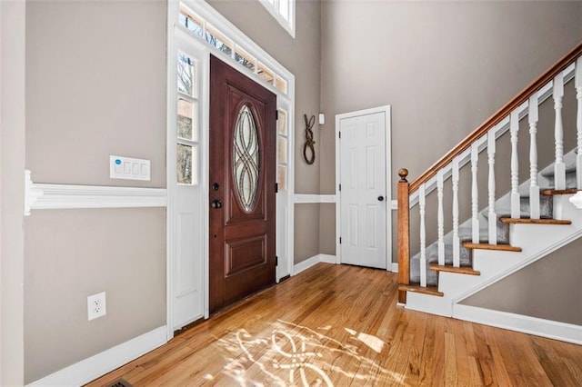 foyer entrance with a wealth of natural light, wood finished floors, and stairs