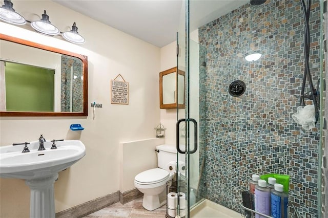 bathroom featuring a shower stall, toilet, and baseboards