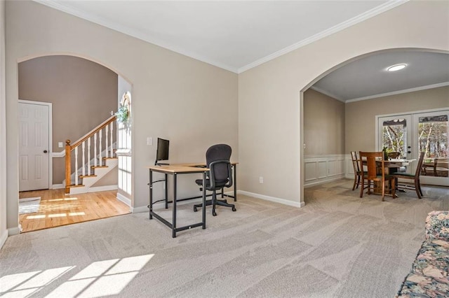 carpeted office space featuring arched walkways, wainscoting, french doors, and crown molding