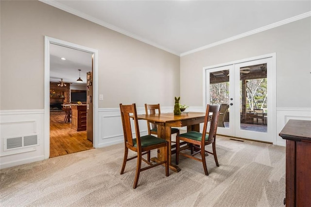 dining area featuring light carpet, visible vents, french doors, and ornamental molding