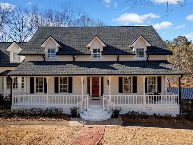 view of front of house with roof with shingles, covered porch, and brick siding