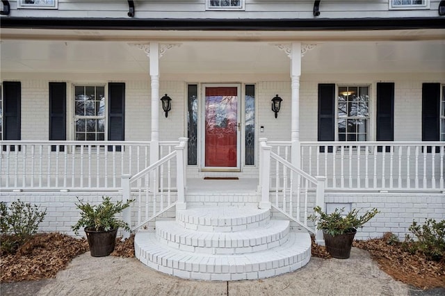 doorway to property with brick siding and a porch