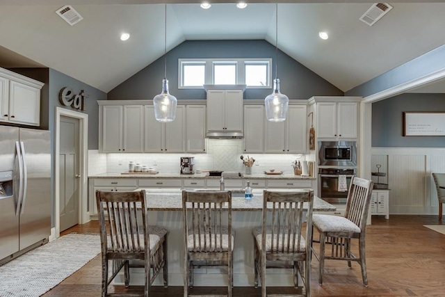 kitchen featuring white cabinetry, stainless steel appliances, a center island with sink, vaulted ceiling, and dark hardwood / wood-style flooring