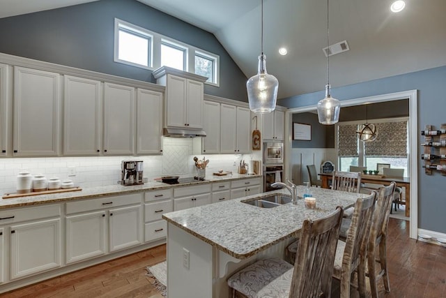 kitchen featuring a kitchen breakfast bar, hardwood / wood-style flooring, white cabinetry, appliances with stainless steel finishes, and sink