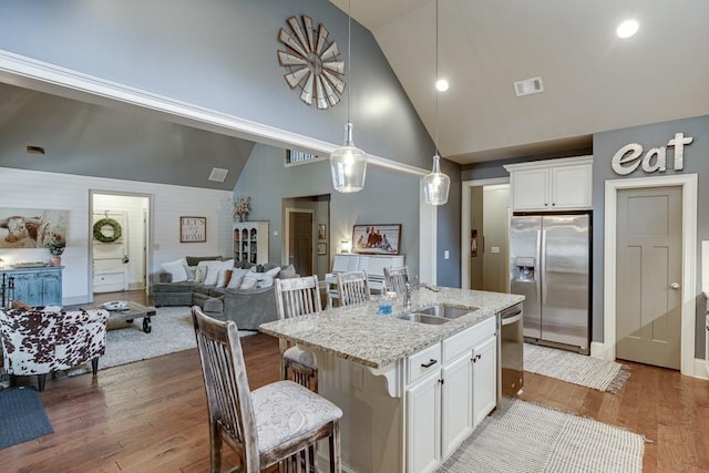 kitchen featuring appliances with stainless steel finishes, hanging light fixtures, light wood-type flooring, light stone countertops, and white cabinets