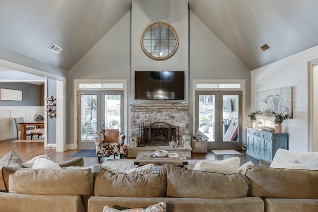 living room featuring plenty of natural light, a stone fireplace, hardwood / wood-style floors, and french doors