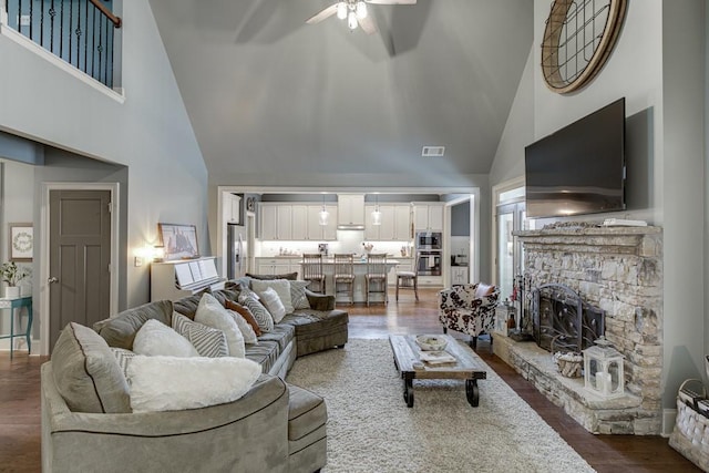 living room with ceiling fan, a fireplace, hardwood / wood-style floors, and high vaulted ceiling