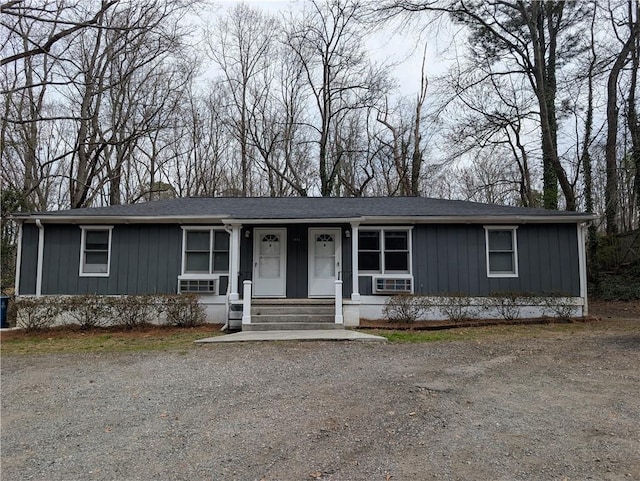 ranch-style house featuring driveway, a chimney, a porch, and board and batten siding