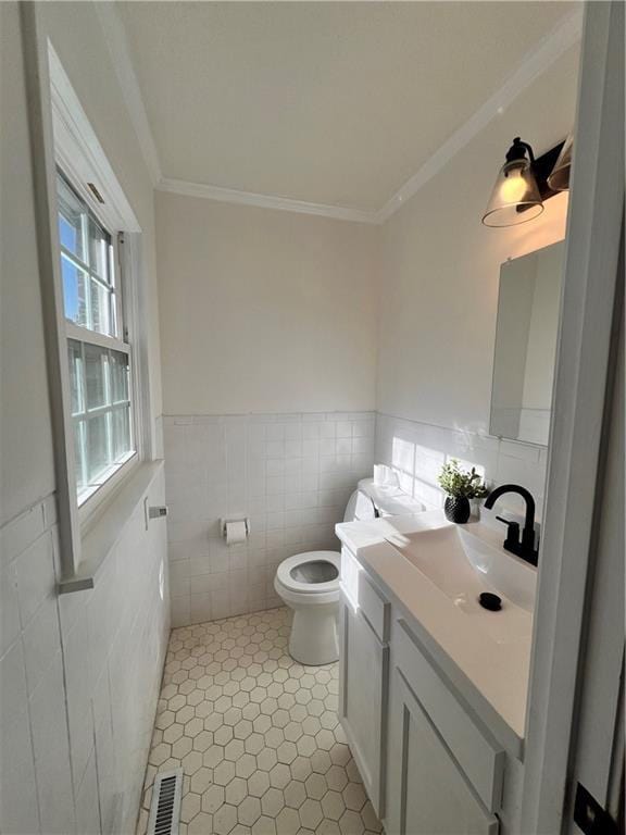 bathroom with vanity, toilet, tile walls, and ornamental molding