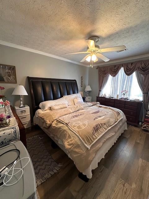 bedroom with a textured ceiling, dark wood finished floors, a ceiling fan, and crown molding