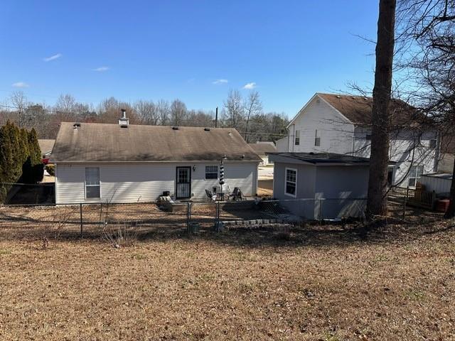 rear view of house featuring fence