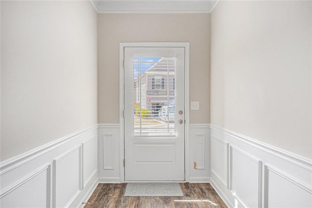 doorway with a wainscoted wall, dark wood finished floors, crown molding, and a decorative wall