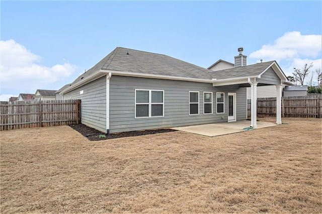 rear view of property featuring a patio area, a fenced backyard, a chimney, and a yard