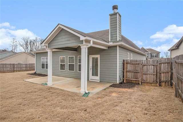 rear view of house featuring a chimney, a patio area, a fenced backyard, and a lawn