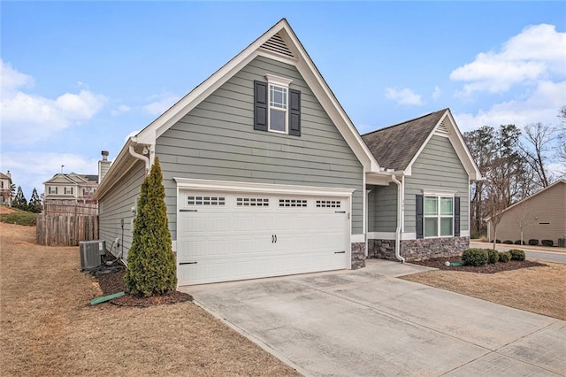 view of front facade featuring stone siding, concrete driveway, central AC, and a garage