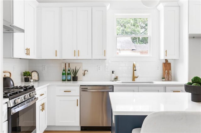 kitchen featuring appliances with stainless steel finishes, tasteful backsplash, white cabinetry, sink, and wall chimney range hood