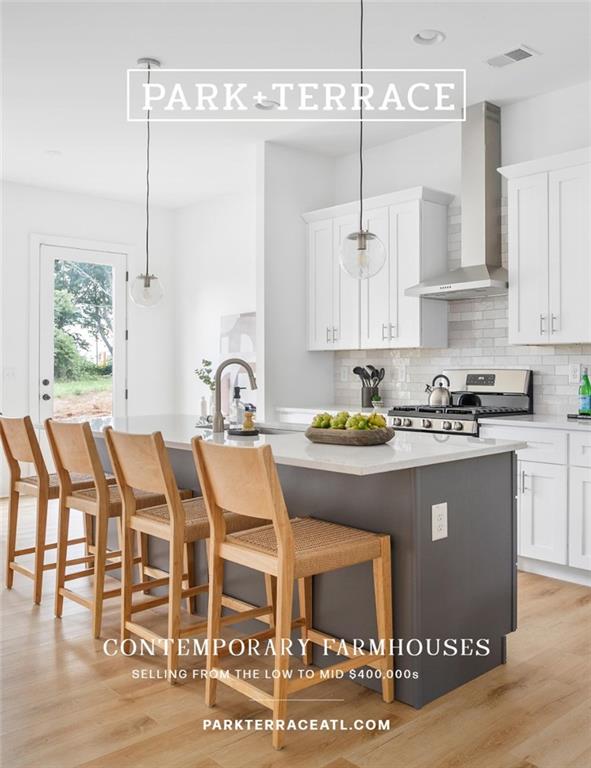 kitchen with pendant lighting, white cabinetry, a kitchen breakfast bar, stainless steel range oven, and wall chimney exhaust hood