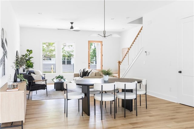 dining space featuring ceiling fan with notable chandelier and light wood-type flooring