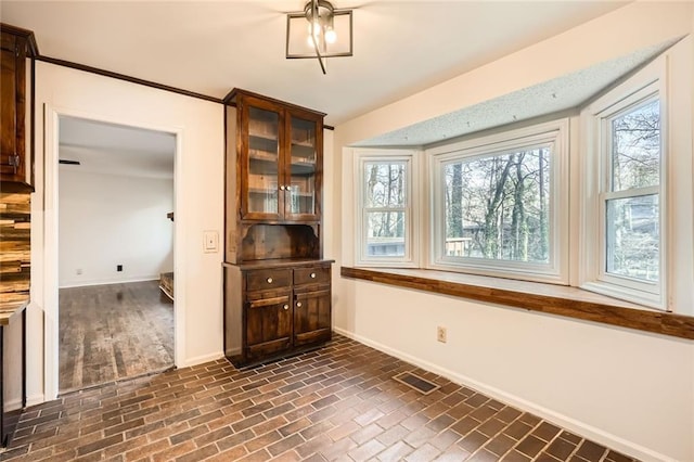 interior space with brick floor, visible vents, and baseboards