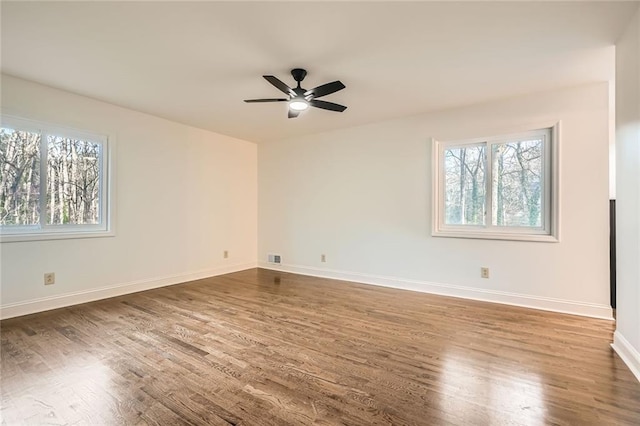 empty room with a healthy amount of sunlight, baseboards, and wood finished floors