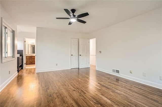 unfurnished bedroom featuring visible vents, a ceiling fan, dark wood-style floors, connected bathroom, and baseboards