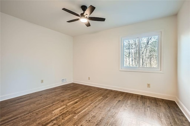 empty room with visible vents, baseboards, dark wood-type flooring, and a ceiling fan