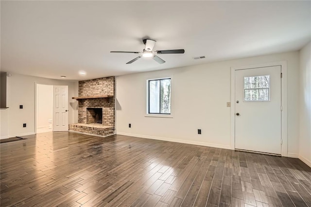 unfurnished living room with dark wood-style floors, a ceiling fan, visible vents, baseboards, and a fireplace