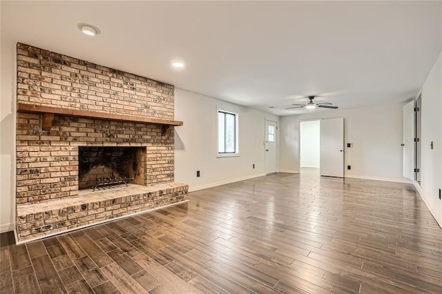 unfurnished living room featuring a brick fireplace, baseboards, a ceiling fan, and wood finished floors