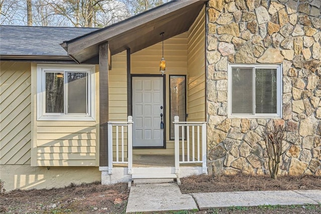 property entrance featuring stone siding and roof with shingles