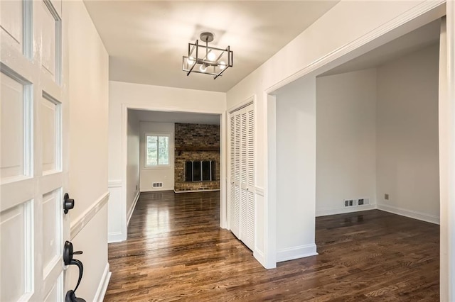 entrance foyer featuring dark wood finished floors, a fireplace, visible vents, and a chandelier