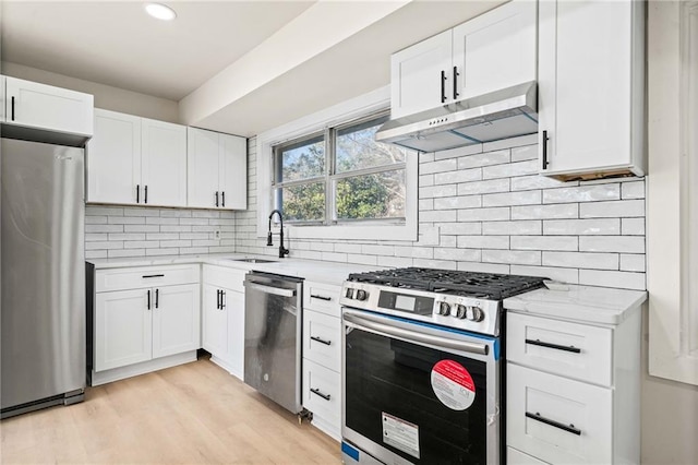 kitchen featuring sink, light hardwood / wood-style flooring, white cabinetry, stainless steel appliances, and light stone counters