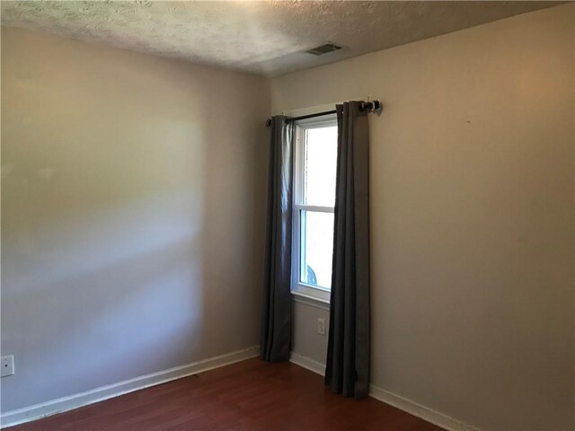 75 Oak Hill Dr, Covington, GA 30016 - empty room with healthy amount of natural light, a textured ceiling, dark wood-style floors, and baseboards