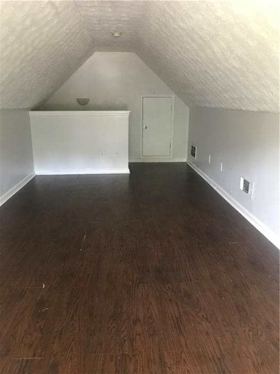 75 Oak Hill Dr, Covington, GA 30016 - bonus room featuring a textured ceiling, dark wood finished floors, baseboards, and lofted ceiling
